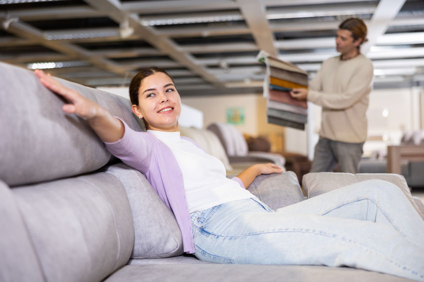 woman sitting on sectional sofa deciding if she wants to purchase it 