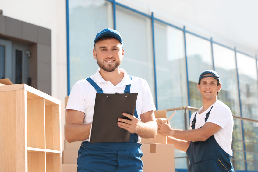 two smiling furniture delivery men delivering furniture to a home 